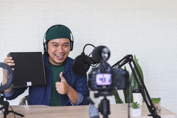 Potrait of excited content creator recording vlog shooting in home studio review product and giving thumbs up about the product. 