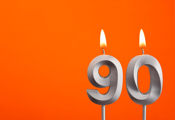 Number 90 - Silver Anniversary candle on orange background