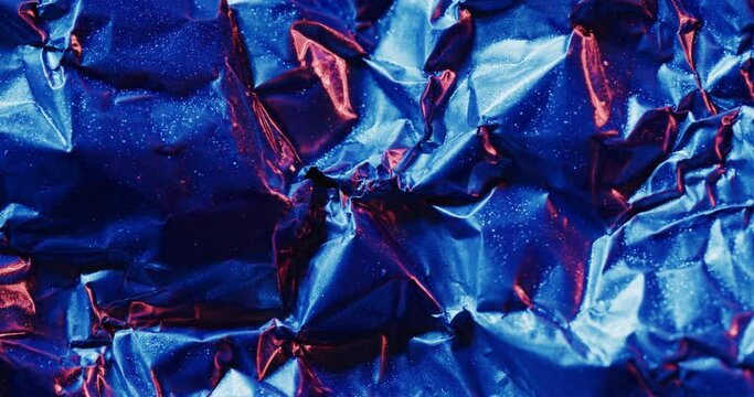 Close up of blue and red crumpled pieces of plastic material in slow motion