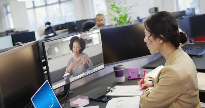 Diverse businesswomen on computer video call with data processing on laptop in office