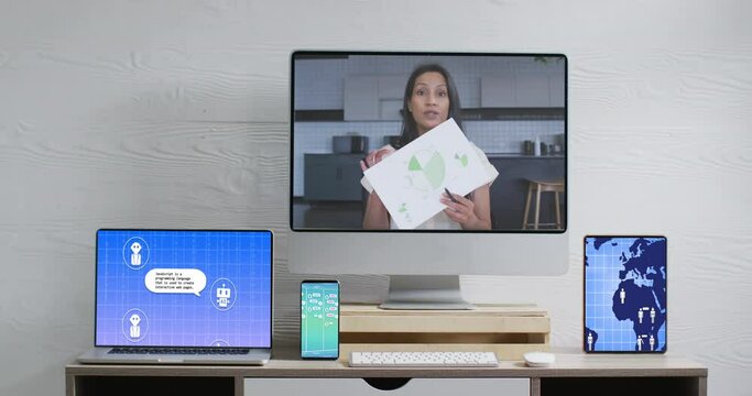 Biracial businesswoman on video call and electronic devices with data processing on screens