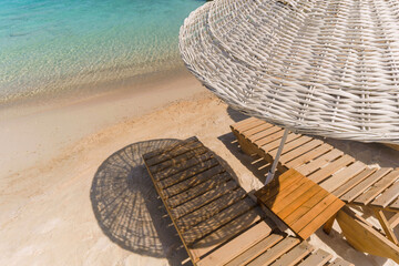 Sunset photo of a calm and beautiful beach. Summer holiday themed visual with sea, sun lounger and beach.