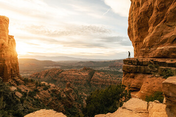 Woman looking down at cliff during dramatic sunset from Cathedral Rock.