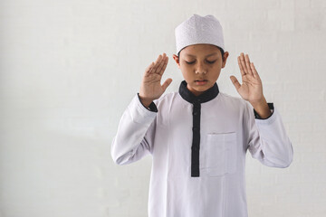 Asian muslim kid pray salah, raising the hands up to the ear lobes. 