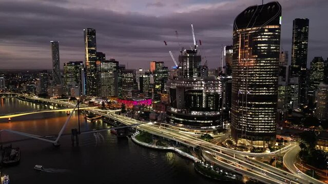 Drone pull away shot of Brisbane city's new Queens Wharf Casino development. Taken from above South Bank and Brisbane River, with heavy traffic on the Riverside Motorway in shot. Taken after sunset.