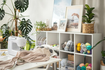 Modern workplace of tailor textile craft designer table with sewing machine and laptop near window