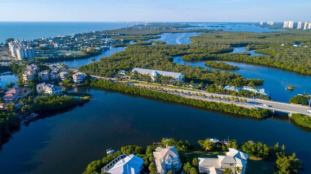 Drone Perspective of Bridge Crossing Bay Waters Surrounded by Mangroves in Naples, Florida with the Gulf of Mexico in the Background