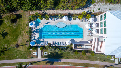 Aerial Drone View of Large Swimming Pool with Lush Landscaping and Umbrellas Next to a Gated...