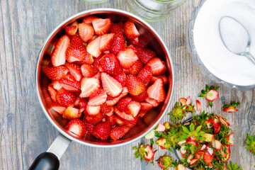 Making jam starts with cleaning and cutting fresh red strawberries