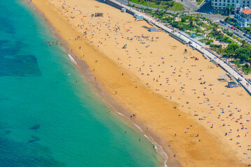 People are enjoying a sunny day at La Concha beach at San Sebastian, Spain