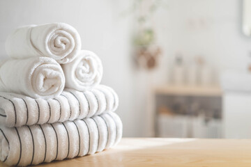 White rolled towels on wooden countertop spa beauty body care hygiene procedure at bathroom. Blurred background - obrazy, fototapety, plakaty