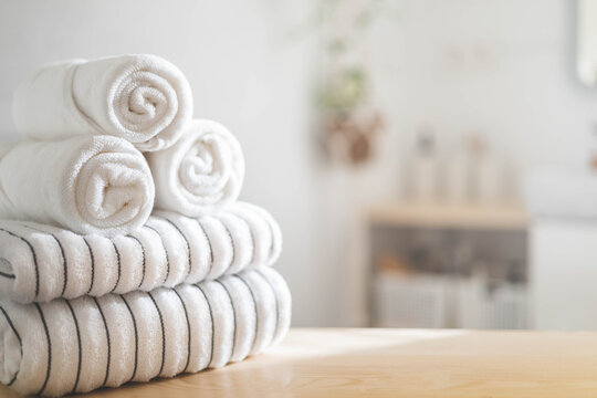 White rolled towels on wooden countertop spa beauty body care hygiene procedure at bathroom. Blurred background