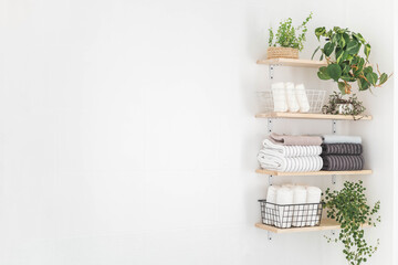 Towels roll neatly folded metallic basket arrangement wooden shelves minimal bathroom interior