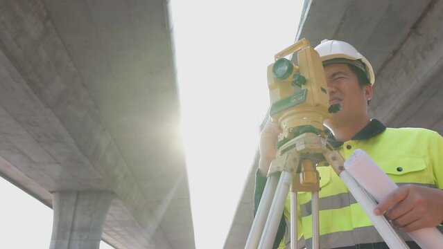 Asian surveyor diligently at road construction site, Surveyor equipment. Highway. Slow motion