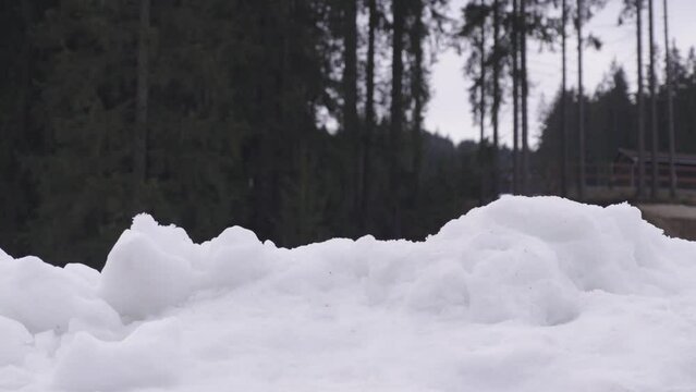 A boy in a blue helmet is peeking mischievously from behind a pile of snow.