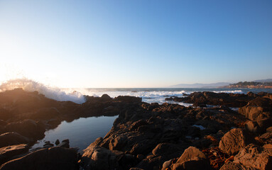 Obraz premium Wave crashing into rocky central California coastline during golden hour at Cambria California United States