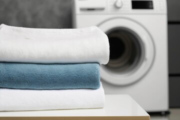 washing machine, stack of towels on a table in the laundry room
