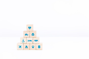 Wooden block stacking on white table and background. healthcare and insurance icon on wood cube arranged in a pyramid. copy space and isolated.