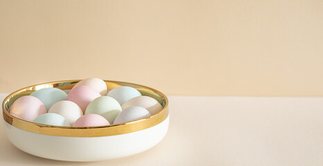 Pastel colored Easter eggs in white bowl on a table