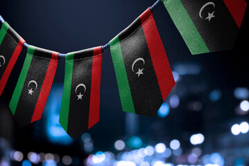 A garland of Libya national flags on an abstract blurred background - obrazy, fototapety, plakaty