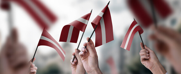 A group of people holding small flags of the Latvia in their hands