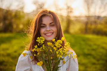 Beautiful woman in a white dress with a bouquet of yellow wildflowers walking in a field 