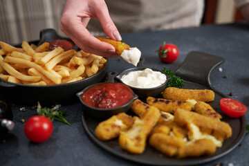 Woman dips Cheese fried mozzarella stick into dip sauce