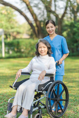 Fototapeta premium Young asian care helper with asia elderly woman on wheelchair relax together park outdoors to help and encourage and rest your mind with green nature.