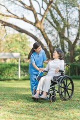 Fototapeta premium Young asian care helper with asia elderly woman on wheelchair relax together park outdoors to help and encourage and rest your mind with green nature.