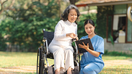 Young asian care helper with asia elderly woman on wheelchair relax together park outdoors to help and encourage and rest your mind with green nature. physical health check
