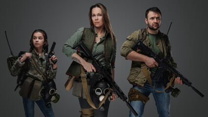 Studio shot of female killer with man and young girl in setting of post apocalypse.