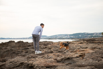 Man walking with his dog during the walk by rocky seacoast - 586045276