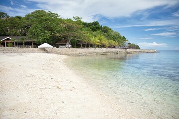 Idyllic, secluded beach of Siquijor in the Philippines with white sand and crystal clear water, trees grow along the beach.