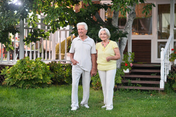 A beautiful elderly couple walks near their house 