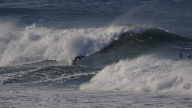 A jet ski photographer takes pictures of a surfer riding a big wave.