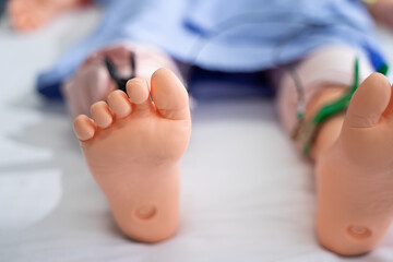 A close-up of a patient mannequin's feet lying on a patient bed