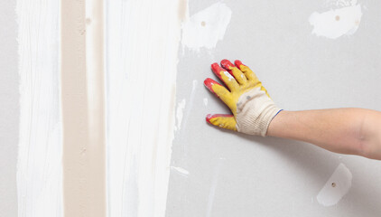 Hand of a worker with gloves on a plaster wall