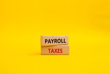 Payroll taxes symbol. Concept word Payroll taxes on wooden blocks. Beautiful yellow background. Businessman hand. Business and Payroll taxes concept. Copy space