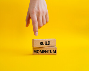Build momentum symbol. Wooden blocks with words Build momentum. Beautiful yellow background. Businessman hand. Business and Build momentum concept. Copy space.