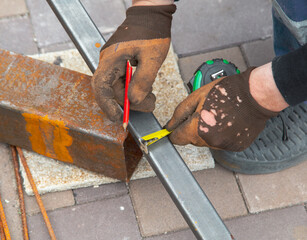 A worker measures metal at a construction site.