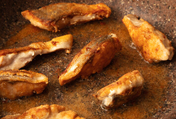 The fish is fried in a frying pan in oil. Close-up.