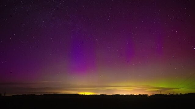 Beautiful footage of the Northern Lights in a purple sky with yellow-green shine and flickering stars. Time Lapse
