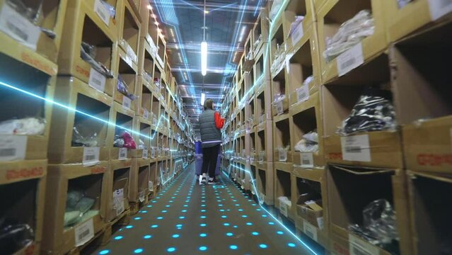 Working on a large modern warehouse. Woman walking through the warehouse, futuristic concept. Visualization of modern technologies in the factory. The concept of modern production
