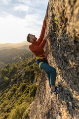 man climbing at sunset in the mountains with the forest in the background, copy space, business, security, trust