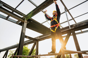 Fototapeta premium Asian construction worker wearing safety body working at height factory roof steel structure