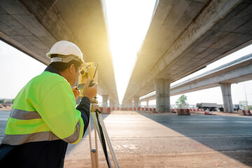 Asian civil engineer surveying highway construction with theodolite
