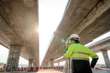 Asian civil engineer surveying highway construction with theodolite