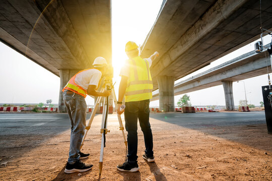 Asian civil engineer team working with theodolite and highway construction drawing paper Civil workers surveying at the road construction site