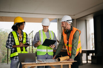 Contractor and architect looking at plan, tablet, laptop and talking about working on big project. Building in construction process interior. team work .