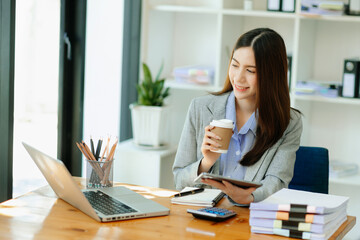  Working woman concept a female manager attending video conference and holding tablet, smatrphone and cup of coffee in office